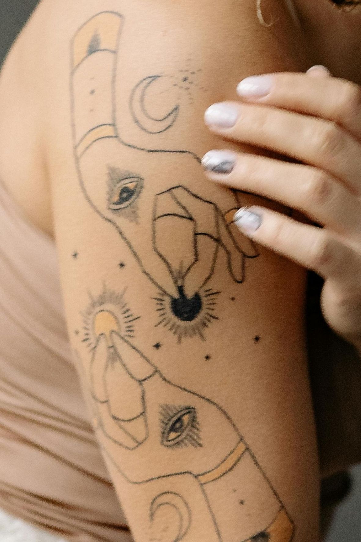 Tatouage artistique aux lignes fines et symboles sur le bras d’une personne dans l’univers du tatouage  à Sainte-Adèle