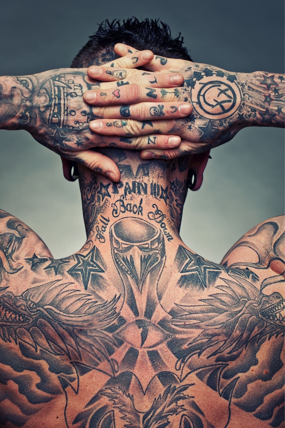 Personne avec de nombreux tatouages visibles sur le cou, les bras et les mains dans l’univers du tatouage  à Sutton